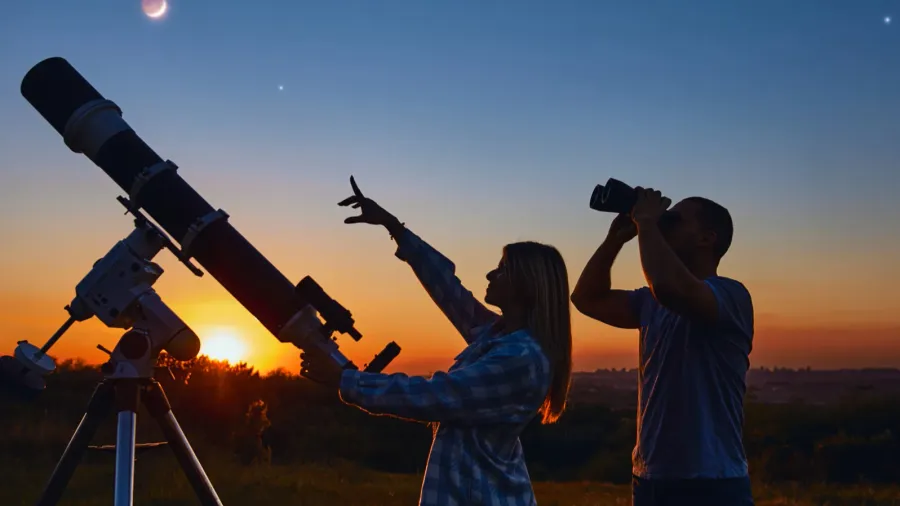 couple stargazing together with a astronomical telescope