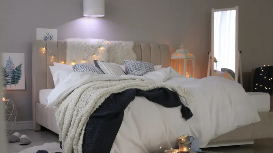 A softly lit bedroom with decorative pillows and a warm throw.