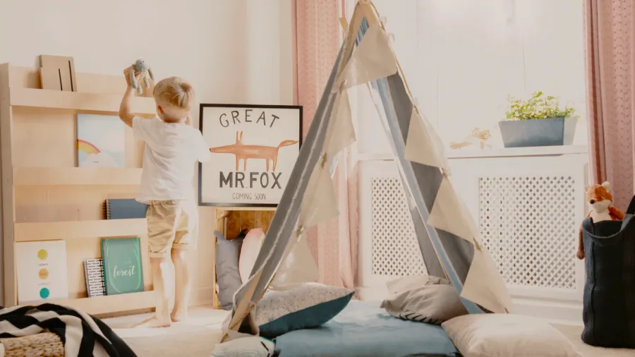A young boy standing in a decorated room with a "Great Mr. Fox" sign and a teepee tent.