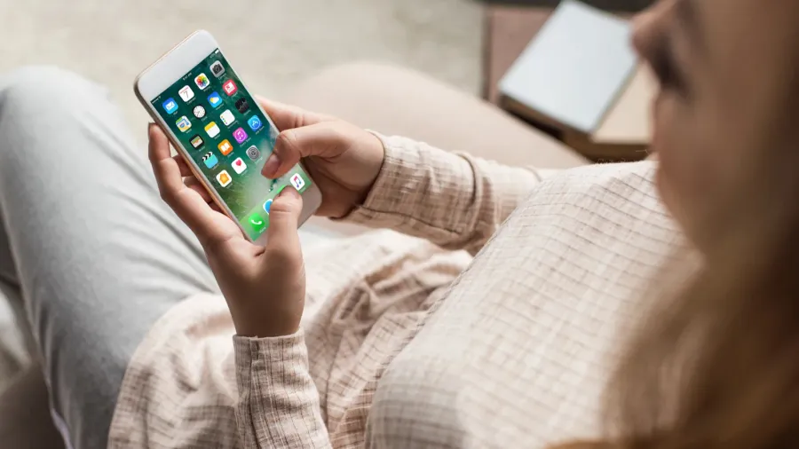 cropped shot of woman on couch using smartphone with ios