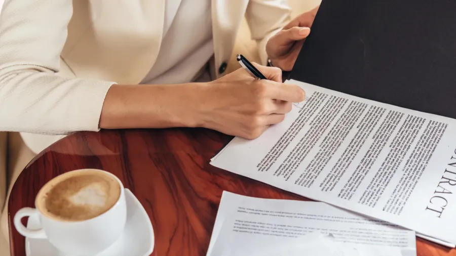cropped view of businesswoman in suit signing contract in private