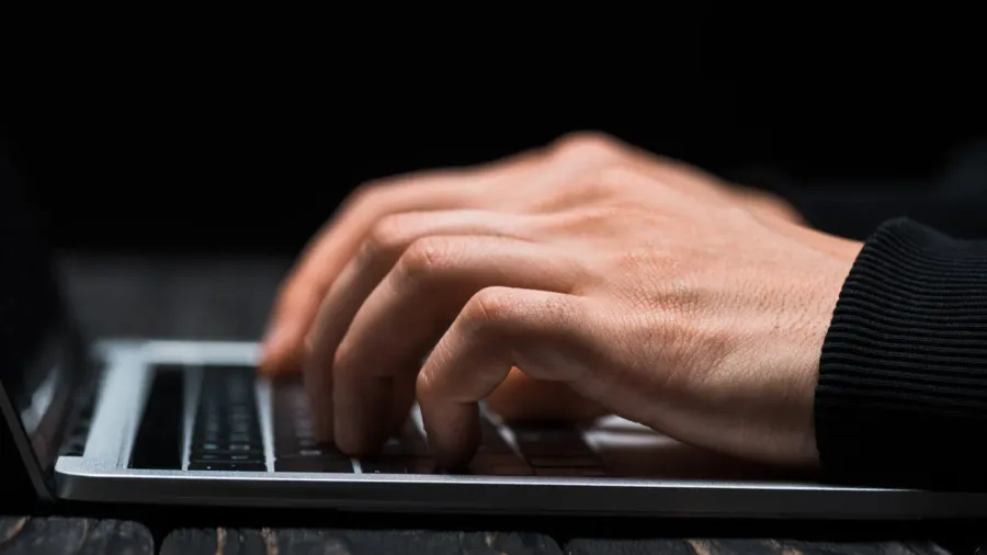 cropped view of hacker typing on laptop keyboard isolated on
