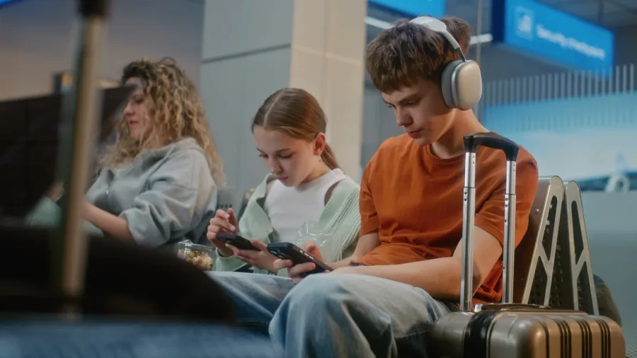 crowded international airport terminal boy and girl teenage siblings using