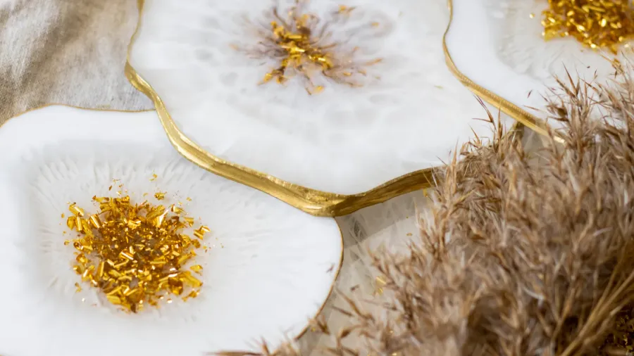 Close-up of white ceramic dishes with gold accents, some containing gold confetti or small gold decorations.