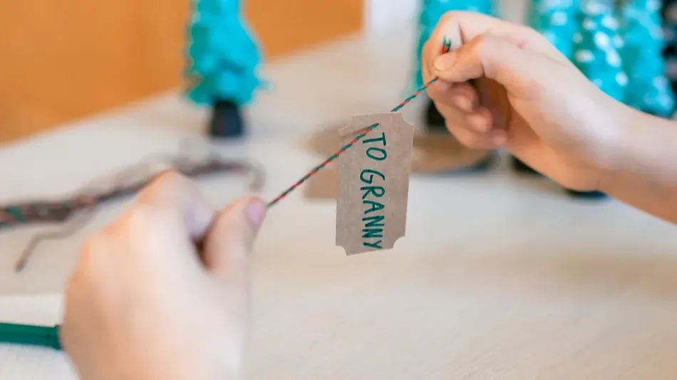 cute girl preparing diy gifts and signing tags to parents