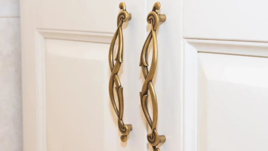 dark handle on the white facade of the cabinet furniture
