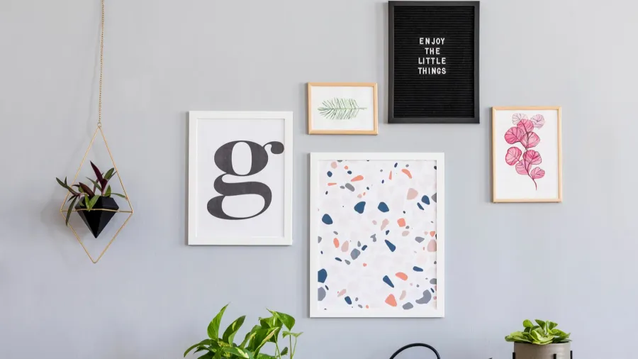 Scandinavian design home interior. Different sizes and colors of frames hanging on the wall. A light hanging from the ceiling.