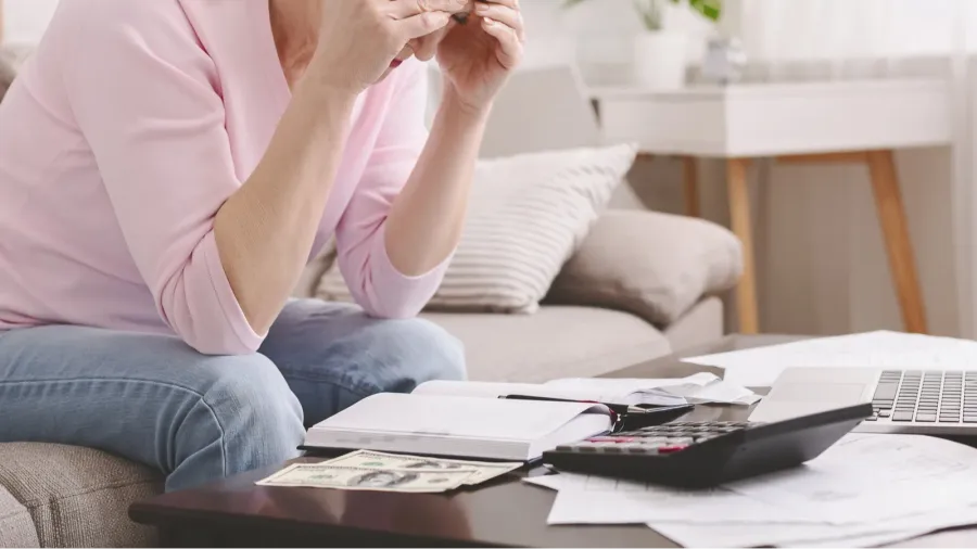 desperate senior woman counting her tiny budget at home