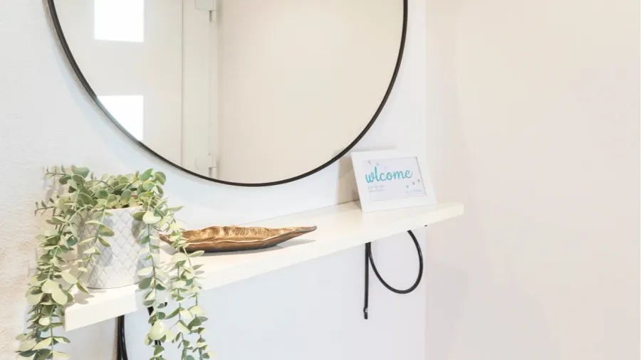 detail of moder round mirror with welcome plaque and