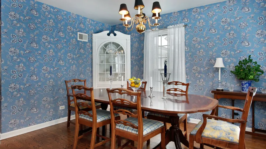 A floral blue wallpaper on the walls in a dining room.