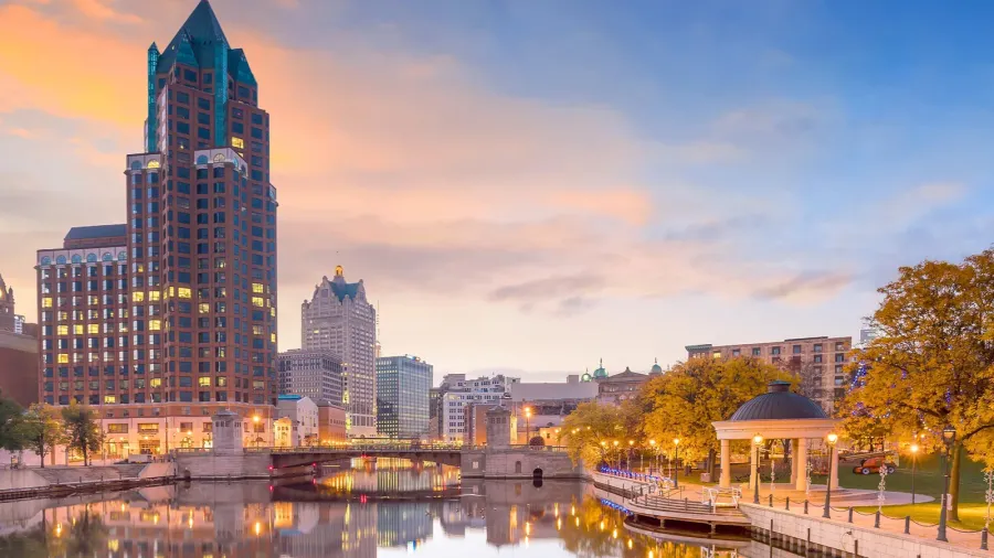 downtown skyline with buildings along the milwaukee river at night