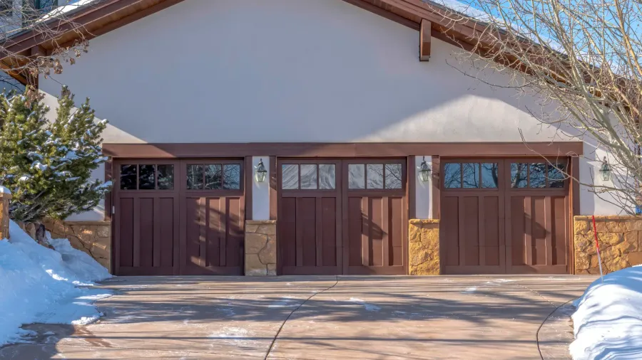 driveway leading to three wooden garage doors with glass panes