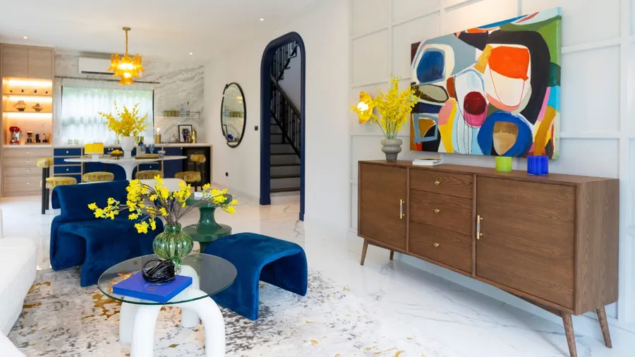A vibrant living space features striking yellow flowers, blue seating, and colorful artwork against a bright and airy backdrop.