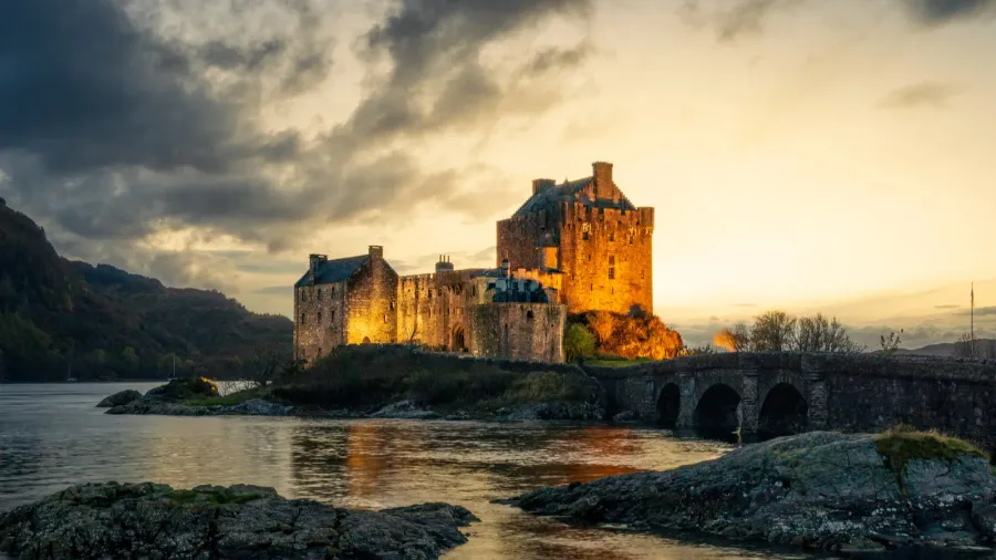 eilean donan scotland castle lit at golden hour on cloudy
