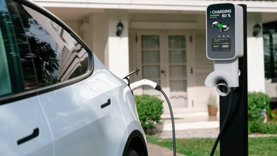 A smart EV charger connected to an electric car in front of the house.