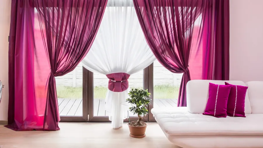 Elegant plum layered curtains hanging in a neutral living room interior.