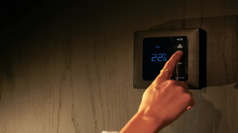 A person adjusting temperature on a digital smart thermostat.