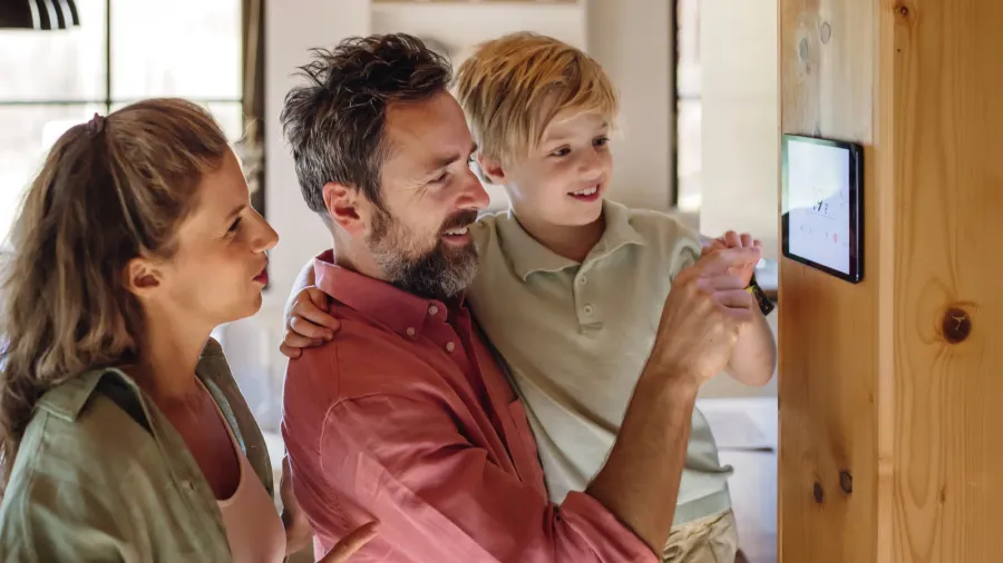 family looking at smart thermostat adjusting or lowering heating temperatures