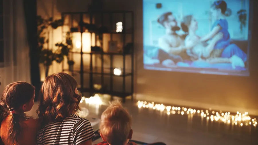 family mother father and children watching projector, TV, movies