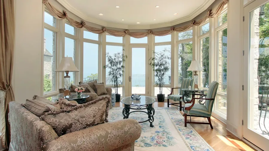 A luxurious living room with panoramic windows offering a sea view, furnished with elegant seating and decor.