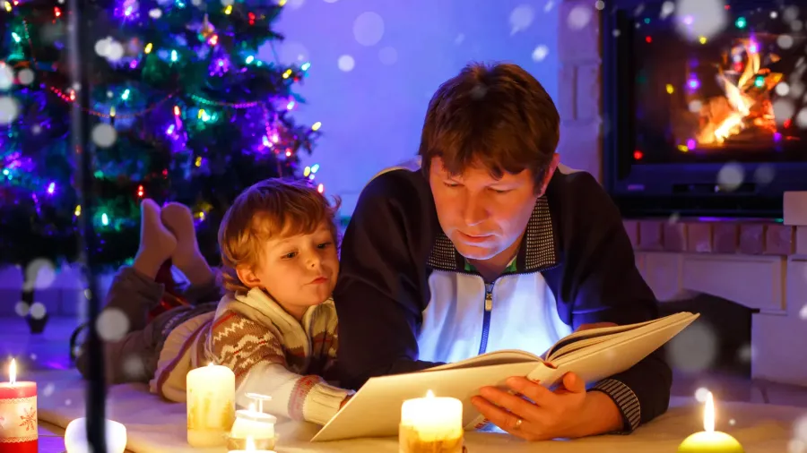 father and cute little toddler boy reading book by chimney