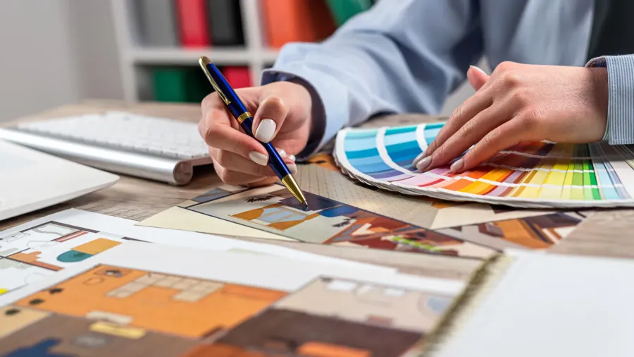 A designer choosing colors from different color palettes for a room according to the furniture.