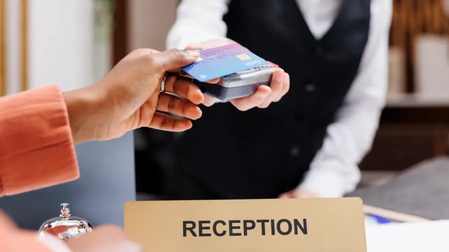 female tourist paying at pos terminal in hotel lobby using