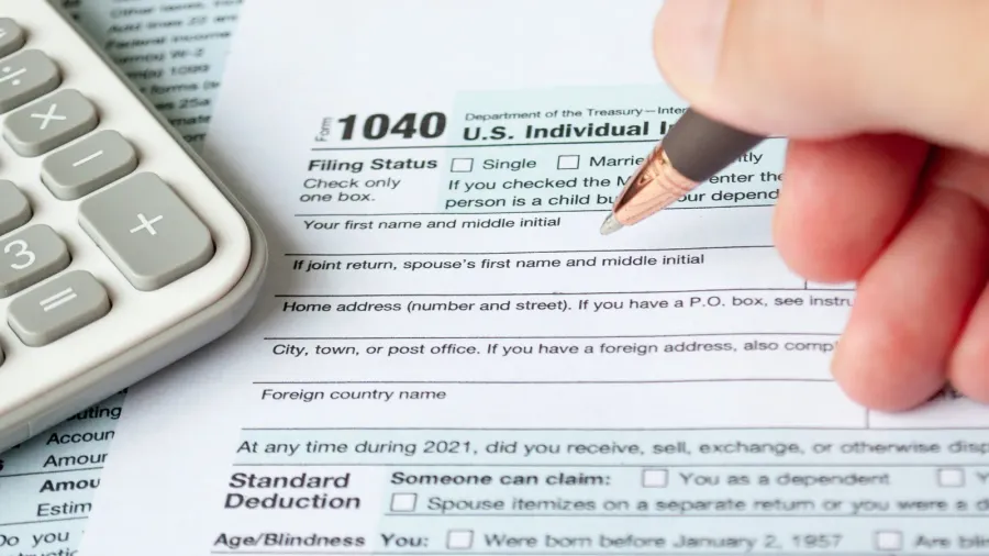 filling up tax form with tax form and calculator background