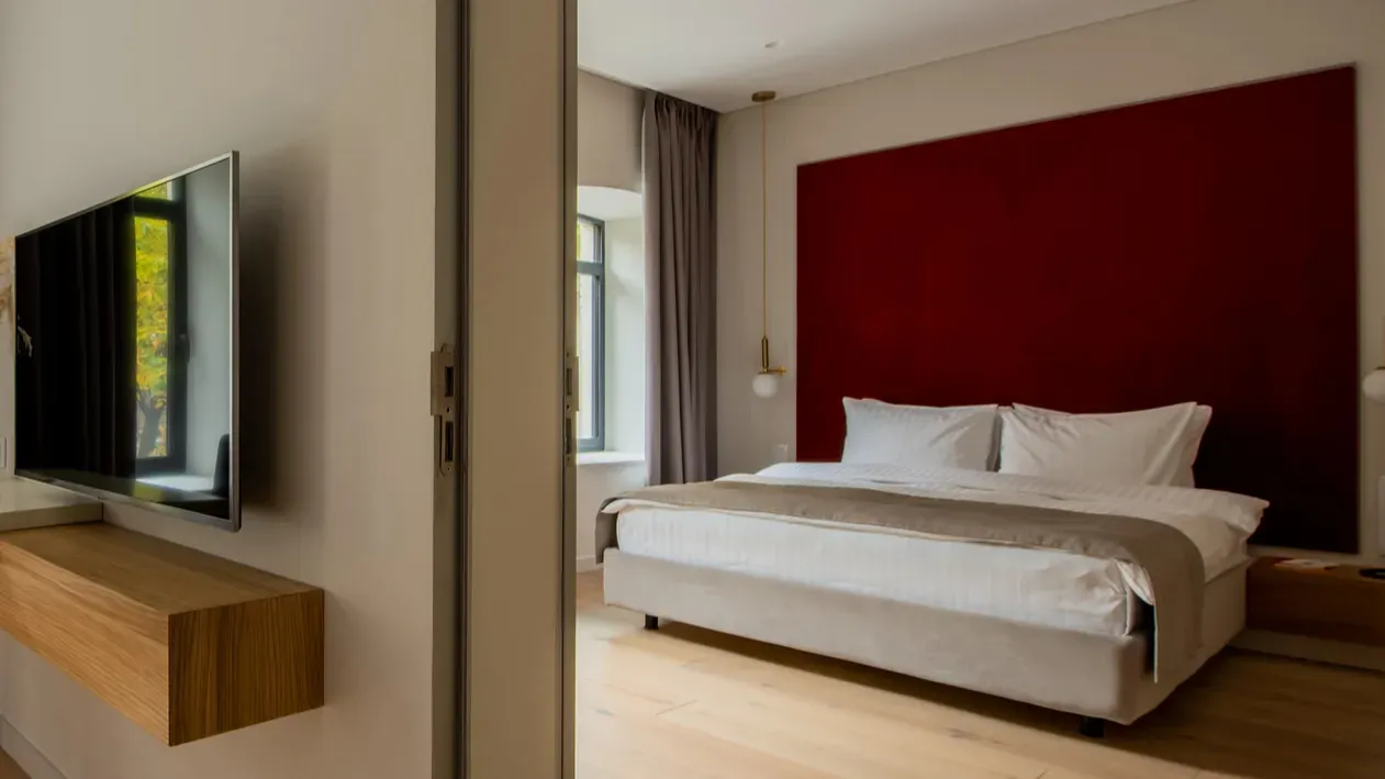 Hotel room with a large bed with white bedding and a bold red headboard.