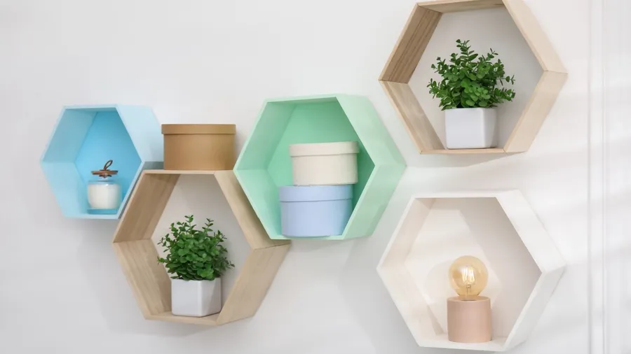 Hexagonal floating shelves on a white wall with plants and decor items in it.