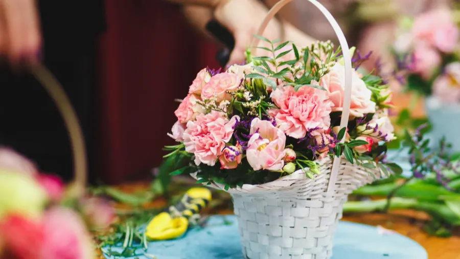 floral workshop  florist makes a bouquet in a basket