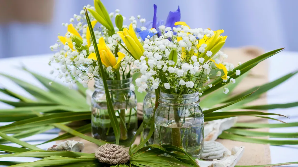 Beautiful floral arrangement in mason jars surrounded by leaves.