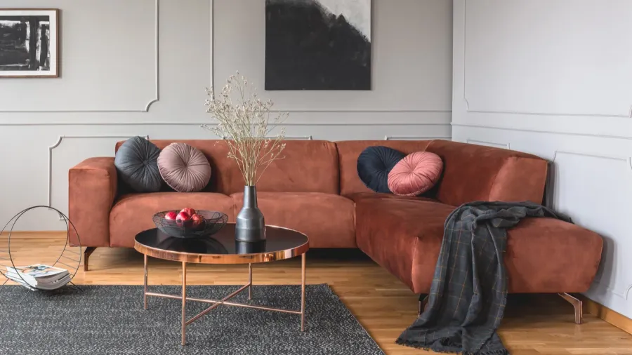 A cozy living room with a large rust-colored sectional sofa, decorative pillows, and a black and copper coffee table.