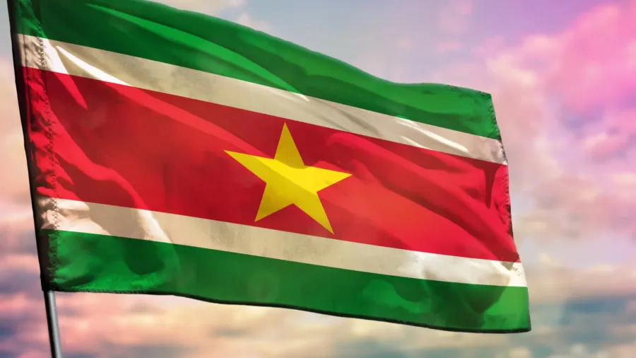 fluttering suriname flag on colorful cloudy sky background prosperity concept