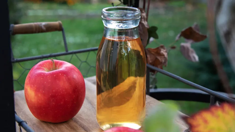 fresh apple juice in the bottle on the wooden tray