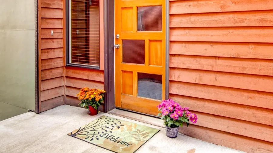 front door with open porch decorated with flower pots