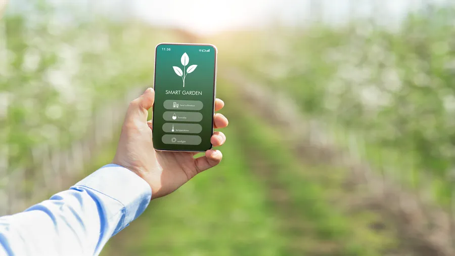 A person holding a smartphone displaying smart garden features.