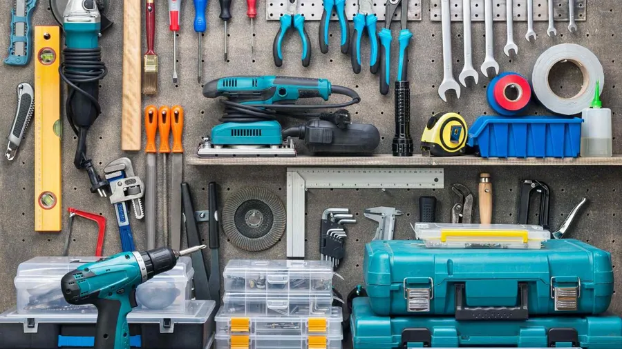 Garage tools workshop with several different tools placed on the table and hanging on wall.