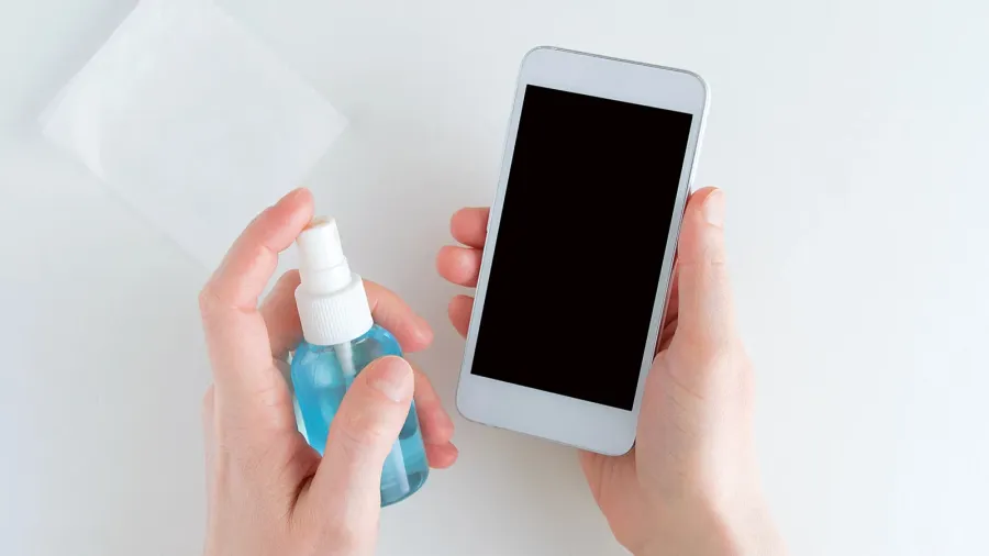 girl hands sanitizes a white smartphone with a disinfectant in