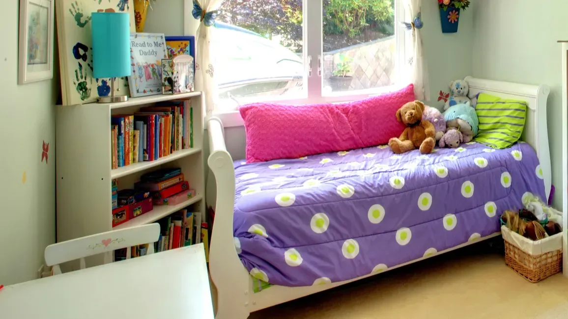 girls bedroom with many toys and purple bed