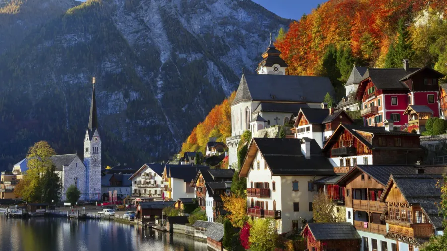 Hallstatt village with church with reflection in the still water of the lake with Alps mountains in the background in Austria.