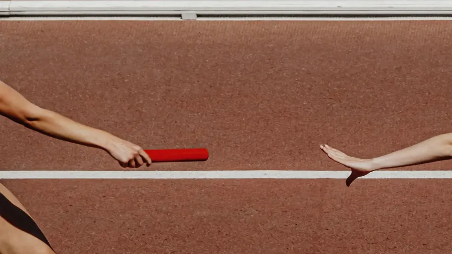 hand female runner passing baton running relay race in summer