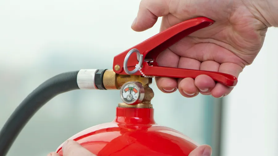 Hand presses the trigger fire extinguisher