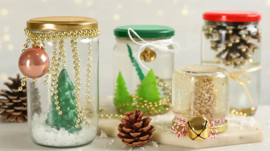 DIY snow globes with pinecones and faux snow around it on a white surface.