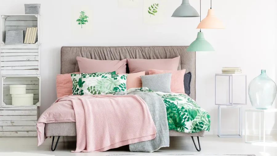 A cozy bedroom featuring a comfortable bed with a variety of colorful pillows and hanging pendant lights.