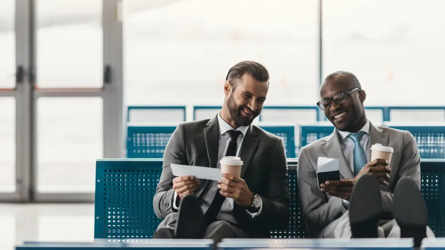 happy business colleagues waiting for flight in airport lobby