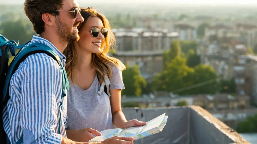 happy smiling couple on vacation sightseeing city with map people