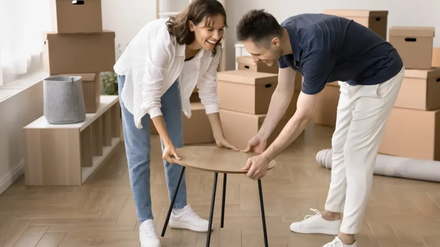 happy young couple carrying new bought coffee table into spacious