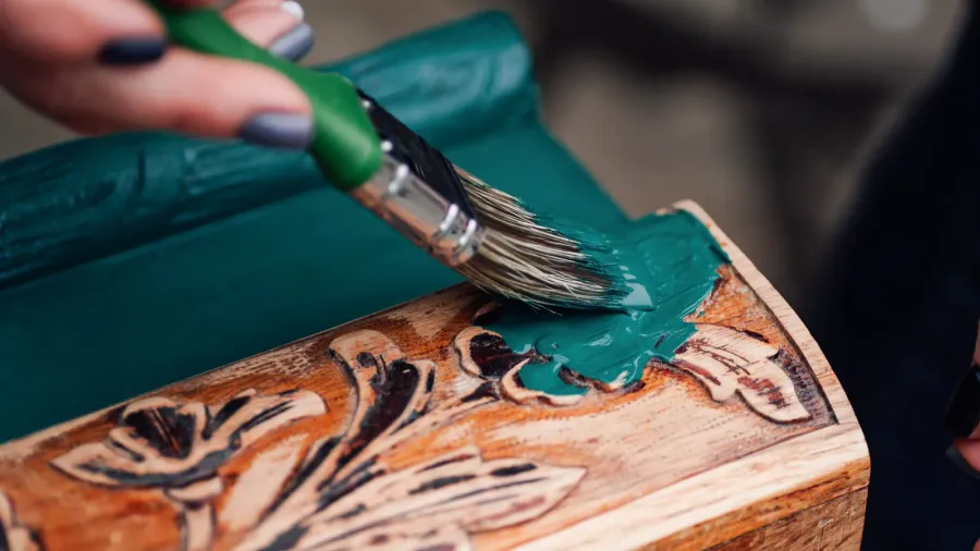 A woman painting an old dresser in bright color.