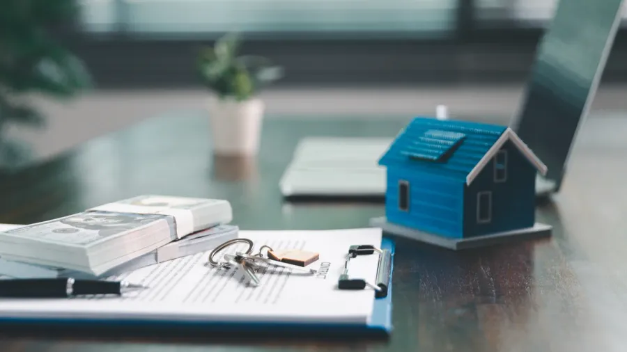 house model placed on table alongside coins paperwork symbolizes real